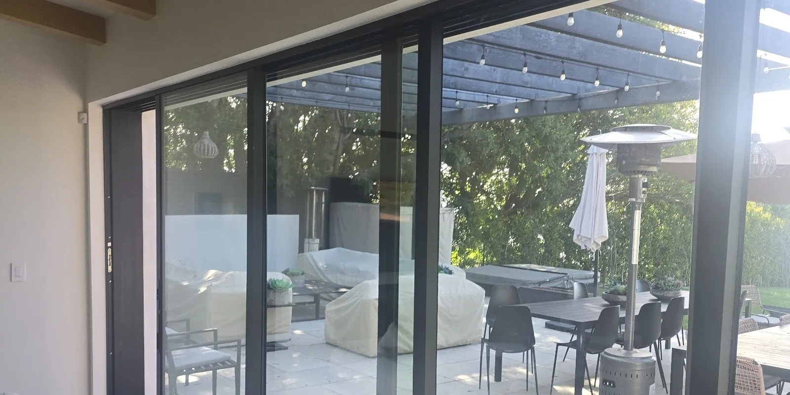 Fleetwood multi-slide doors opening to a pergola patio in Los Angeles, installed by Versa Glass Co.