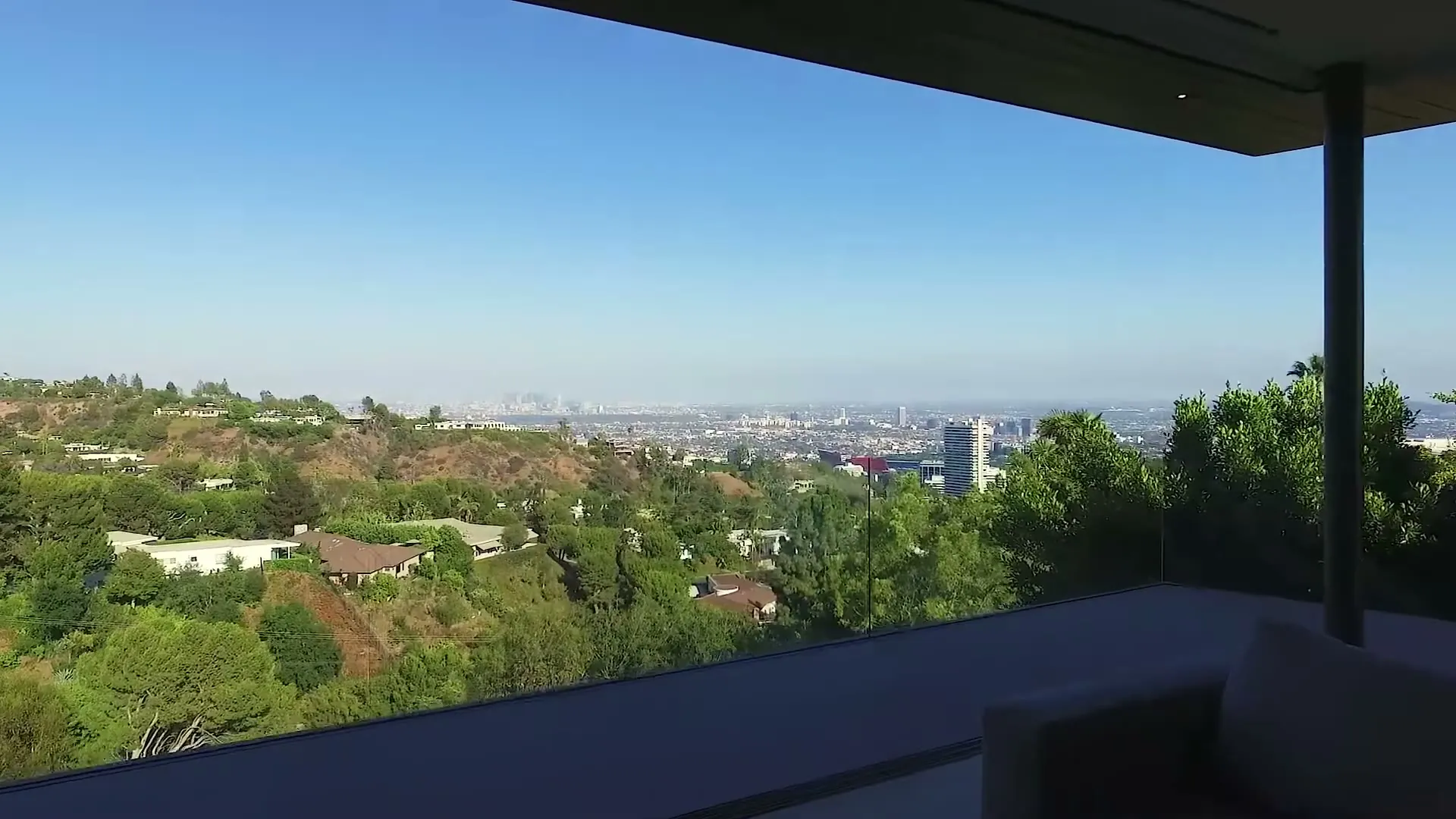 Corner glass bedroom with a frameless glass balcony railing at 1520 Gilcrest Drive, Beverly Hills