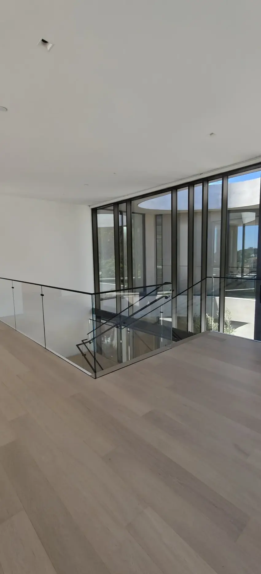 Glass stair guardrail beside a Fleetwood window wall in a Los Angeles residence