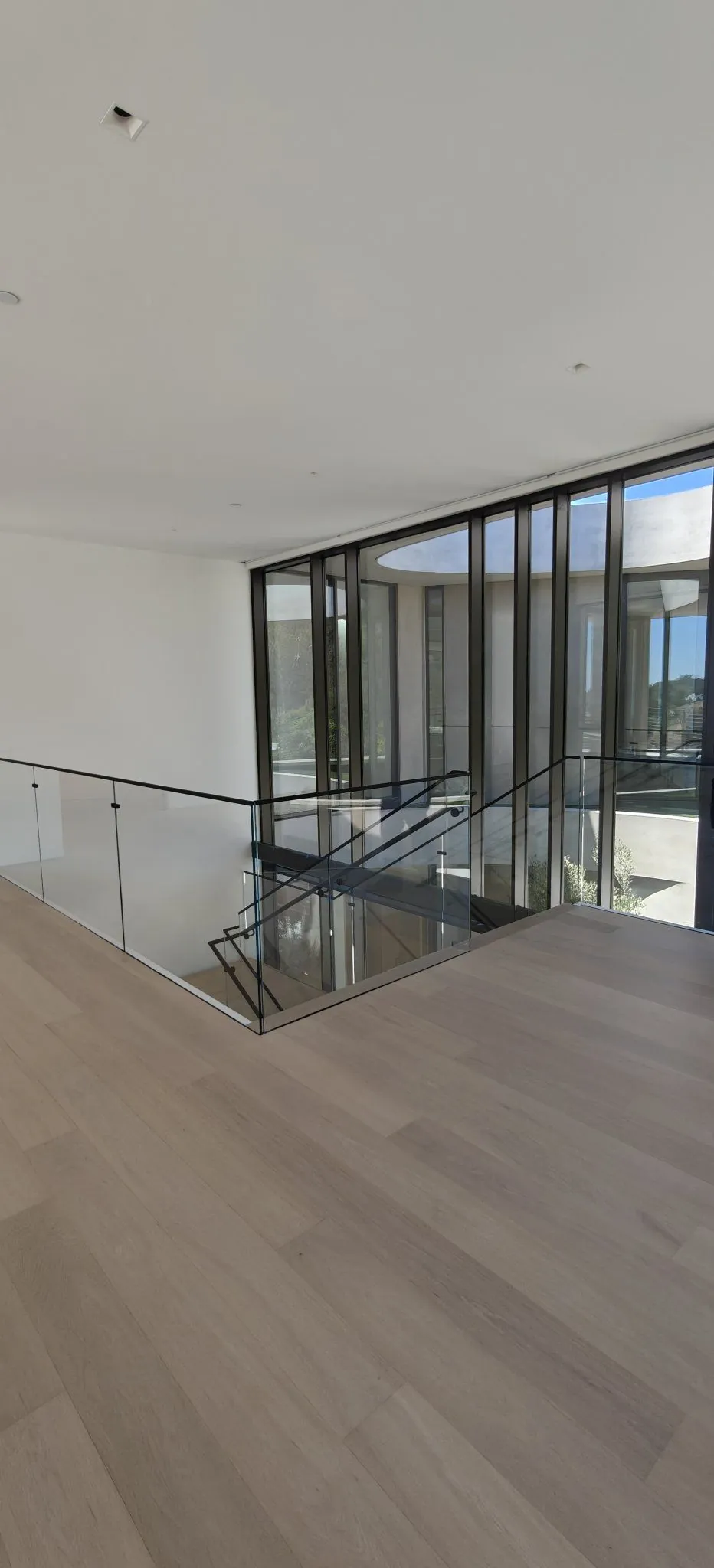 Glass stair guardrail and upper-level railing beside a window wall in a Los Angeles residence