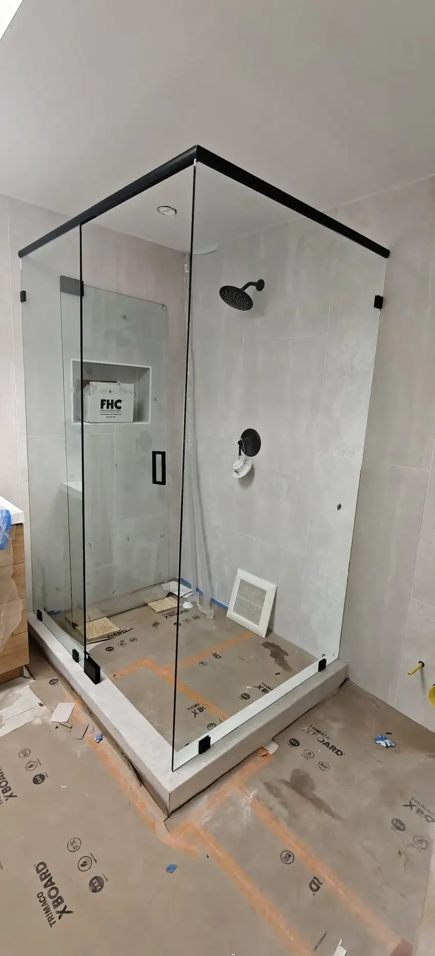 Completed corner frameless shower enclosure with black header bar in Los Angeles