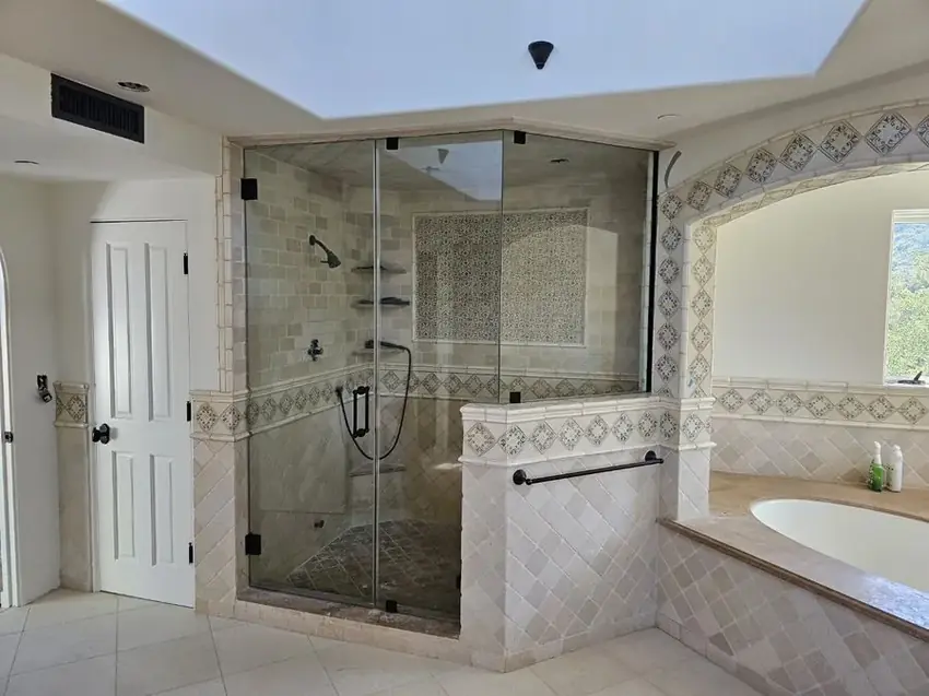 Finished frameless shower enclosure with decorative Spanish tile and matte black hardware in Los Angeles