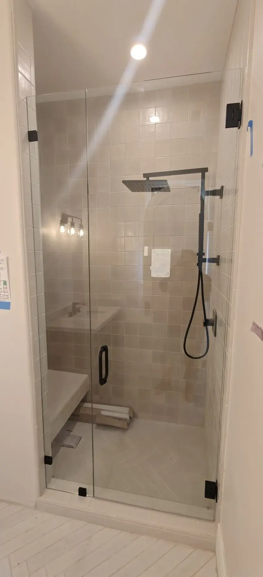 Finished frameless shower door and panel with matte black hardware and beige zellige tile in Los Angeles