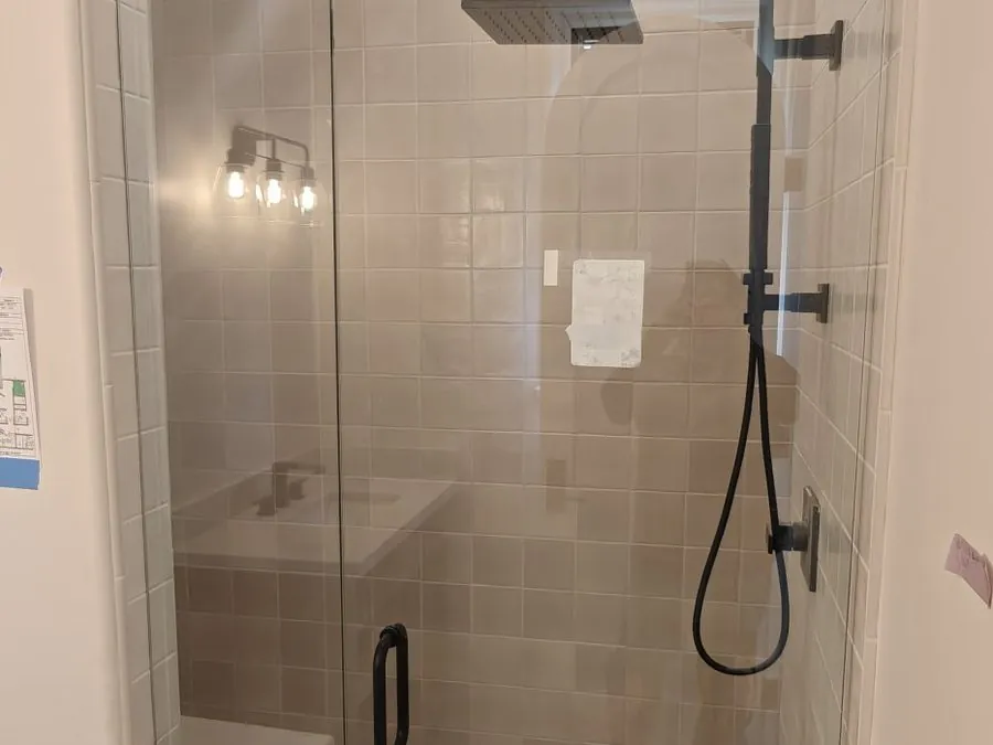 Finished frameless shower door with matte black hardware in a Los Angeles bathroom, installed by Versa Glass Co.